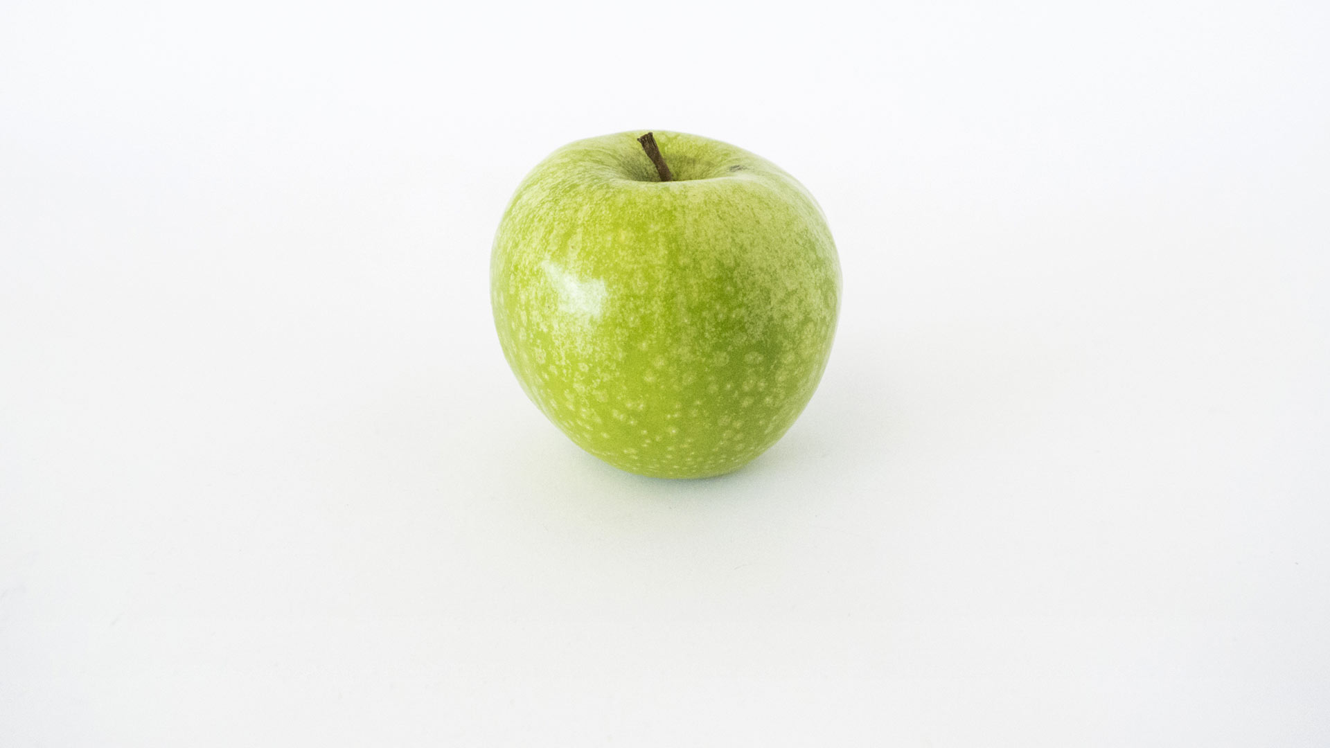 A photograph of a fresh green apple isolated against a white background