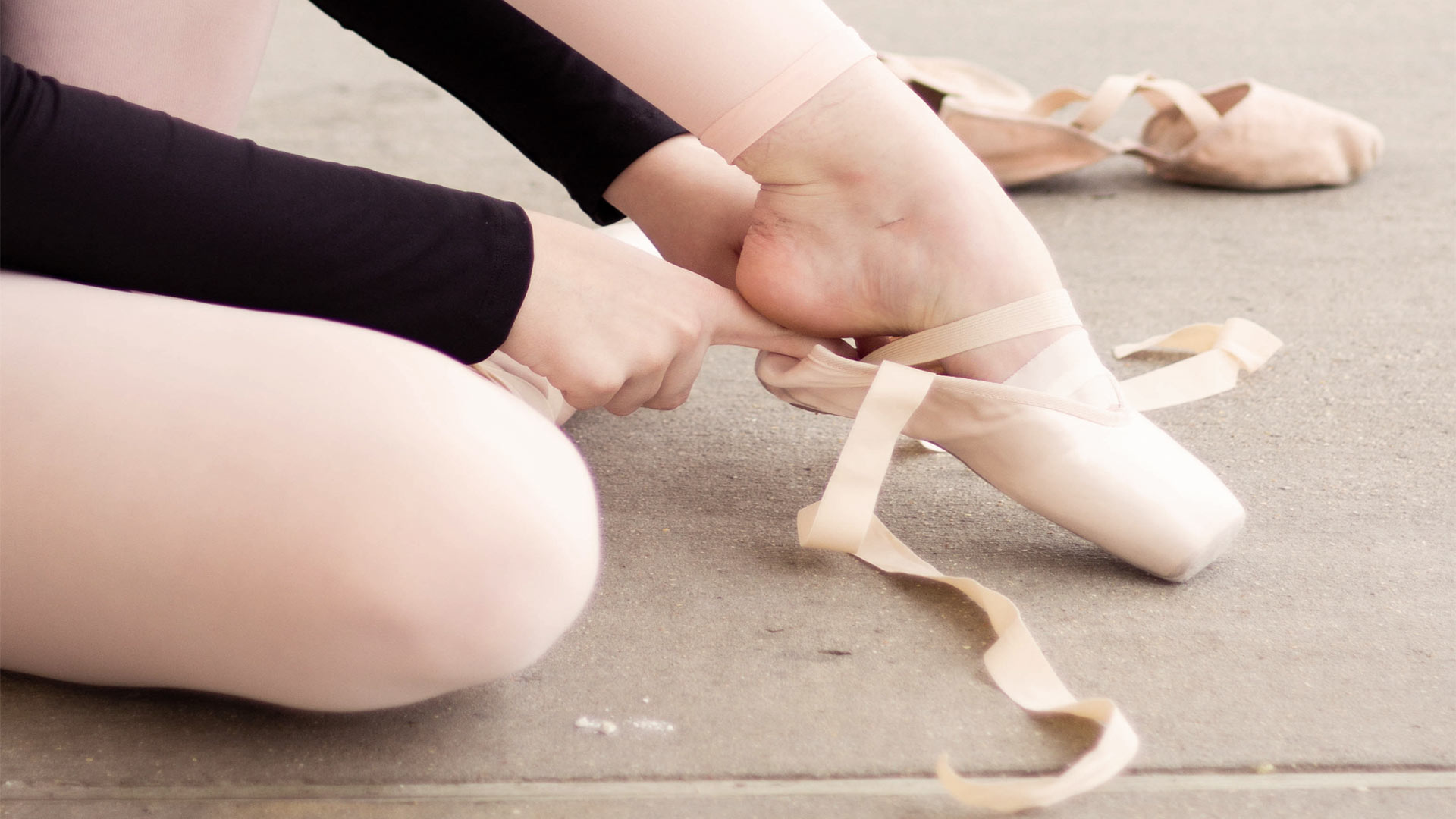 A ballet dancer putting on their shoes and preparing to perform