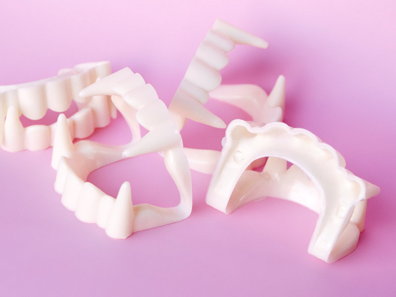 A photograph of four sets of plastic vampire teeth