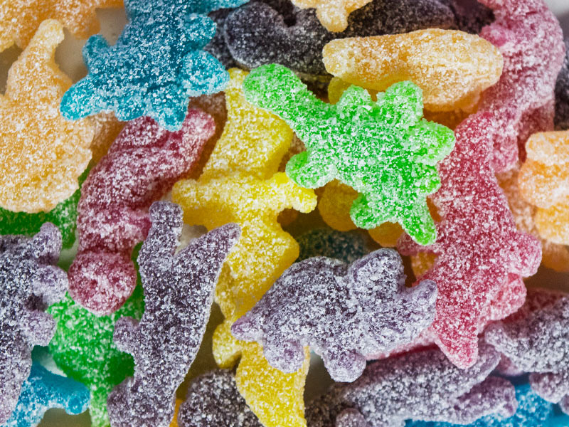 A collection of brightly-coloured gummy dinosaur sweets, encrusted in sugar